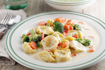 Tortellini with vegetables under cream sauce