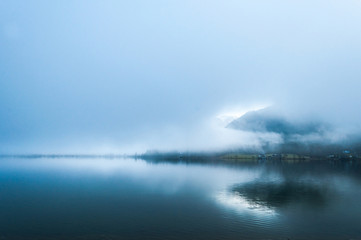 Early foggy  wet morning on the lake between the mountains in Austrian Alps