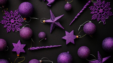 Christmas purple collection, balls and decorative ornaments, on black background. Top view.