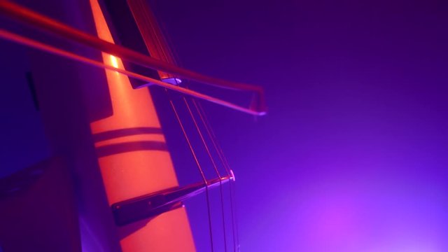 Cellist with electronic cello performs on stage.