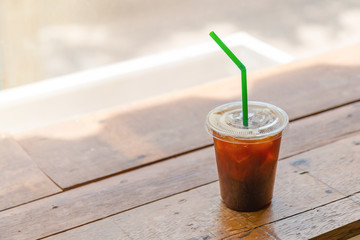 Iced coffee in a plastic cup on the wooden table.