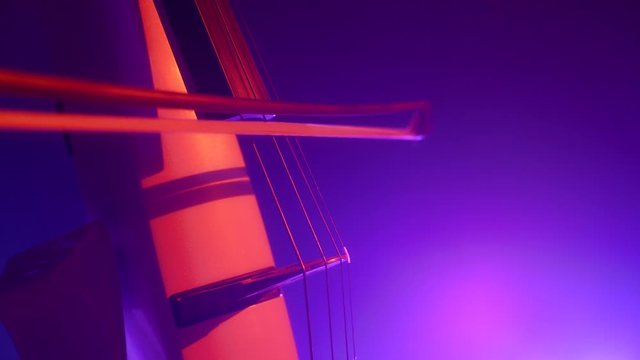Cellist with electronic cello performs on stage.