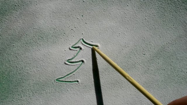 Draw designer Christmas trees with a wooden stick on the snow in bright light on the green bottom layer for decorations in anticipation of the Happy New Year and Christmas 