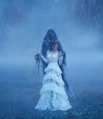 Dark Lord's Bride in white vintage mesh translucent dress and a silver necklace is standing on the...