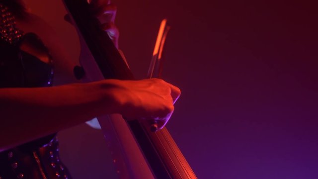 Cellist with electronic cello performs on stage.