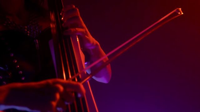 Cellist with electronic cello performs on stage.
