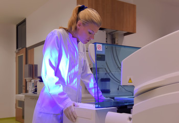 A young student takes up her duties as lab  assistant. She wears a white smock to work  with while...