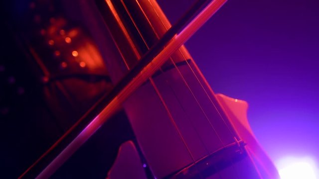 Cellist with electronic cello performs on stage.