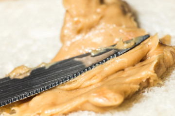 Knife blade smears peanut butter on bread