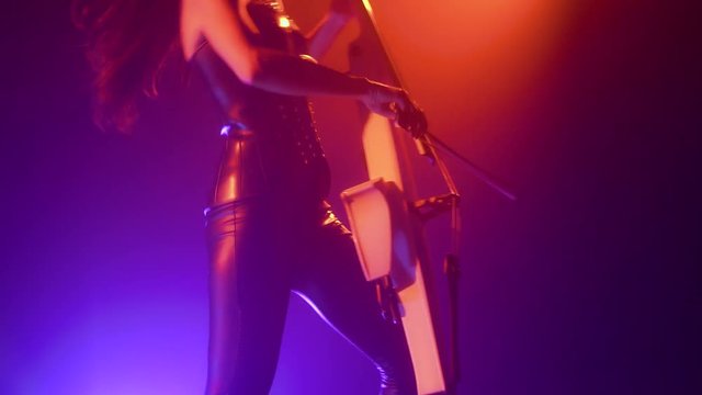 Cellist with electronic cello performs on stage.