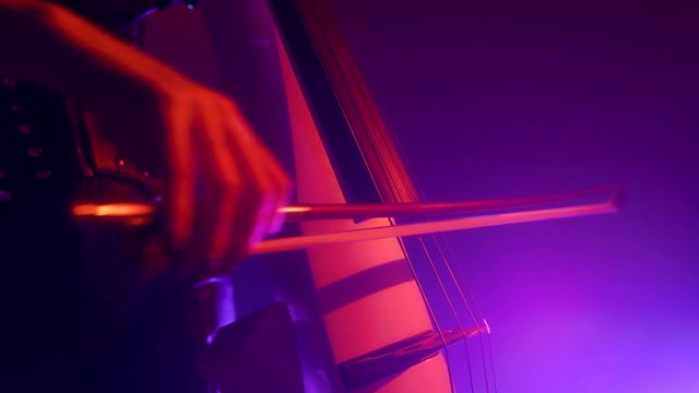 Cellist with electronic cello performs on stage.