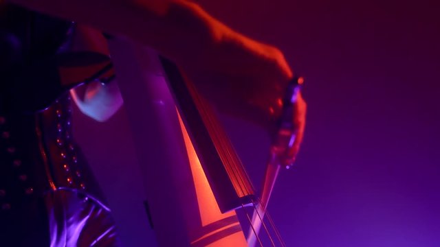 Cellist with electronic cello performs on stage.