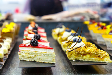 Many different small cakes are on the window of the candy shop.
