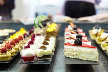 Many different small cakes are on the window of the candy shop.