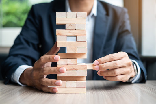 Businessman hand placing or pulling wooden block on the tower. Business planning, Risk Management, Solution and strategy Concepts