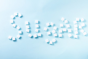 Sugar word in sugar cubes on blue background