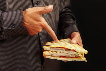 Man in black shirt recommends sandwich on a black background close up