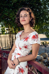 Headshot of beautiful young teen dressed in long flower print dress relaxed and leaning back...