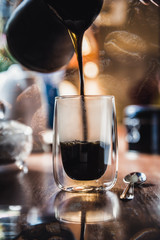 Double exposure of pouring hot coffee into mug and coffee beans