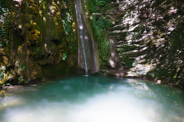 Slope overgrown with ivy and moss with a flowing tranquil waterfall