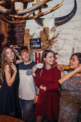 Fototapeta premium Four cool teenagers wearing casual clothes posing for camera in a stylish with hunting lodge interior design.