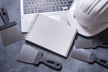 Set of  putty knifes and helmet on grey background
