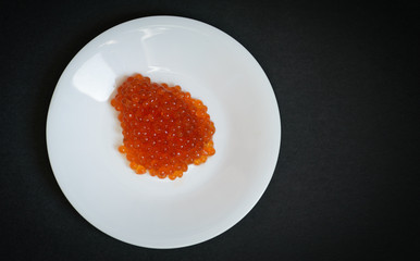 Red caviar on a saucer. Selective focus.