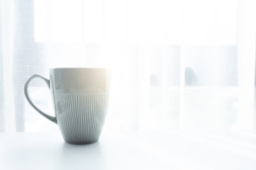 Coffee cup on white table in the morning and sunlight 