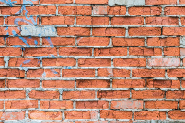 The old building wall of red bricks with cracks, clefts, chips and the parts of plaster
