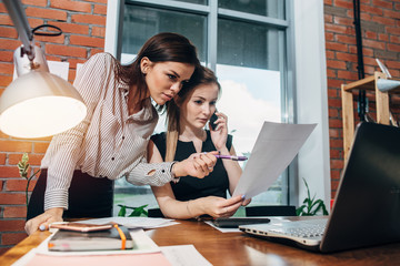 Two young women working with documents in office