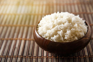 Cooked white rice (Thai Jasmine rice), rice in dark wooden bowl with chopsticks on the wood black bamboo background.