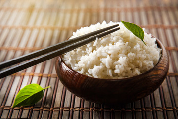 Cooked white rice (Thai Jasmine rice), rice in dark wooden bowl with chopsticks on the wood black bamboo background. - 226346030