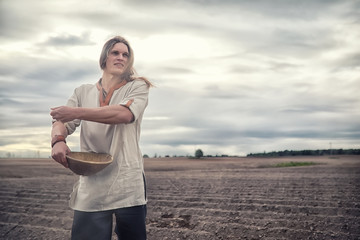 A young peasant sows the field with grain