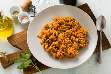 Italian risotto with tomato sauce and green peas, served in a plate on a wooden cutting board. classic Mediterranean cuisine. healthy vegan meal for the whole family