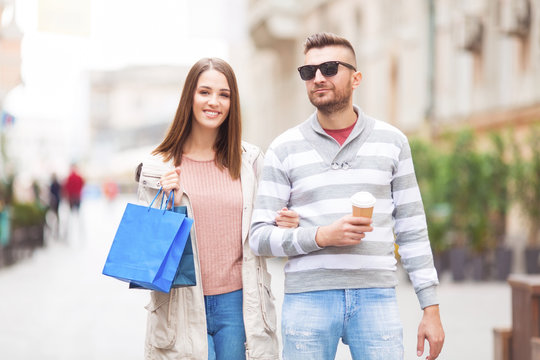 Young couple with shopping bag and coffee outdoors