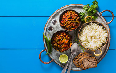 vegan curry with green peas and basmati rice served on a blue table tray, healthy Indian comfort food, copy space