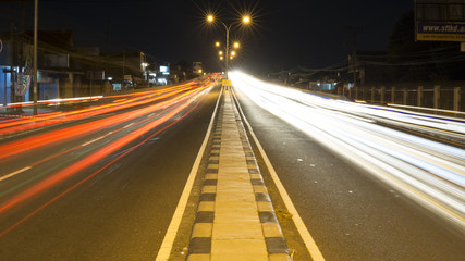 City lights trials of fast moving traffic of cars on the road at night