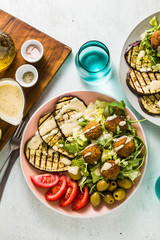 an appetizing dinner or lunch from a salad with tomatoes, grilled eggplants and legume falafel with sesame tahini dressing. Vegan healthy food for the whole family