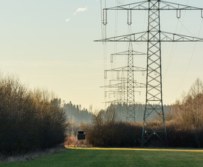 Hochspannungsleitung und Hochsitz vor Wald