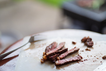 grilled meat cut on plastic cutting board, barbecue party