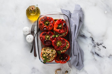 ready baked stuffed peppers in a glass baking dish on white marble table. healthy vegan cuisine for the whole family. comfort food