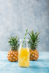 Fresh pineapple juice and ripe pineapple on grey background