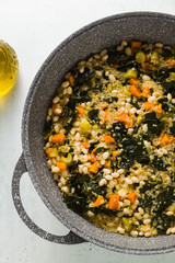 preparing a vegetable soup of kale and white beans in wok pan. healthy vegan cuisine for the whole family. comfort food