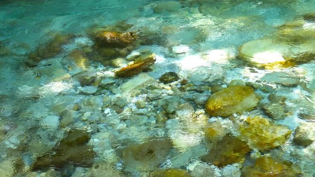 View of The River Soca as its crystal clear water flows in a rocky river bed in Slovenia.
