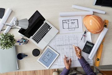 Construction engineer working with various blueprints on his table, view from above