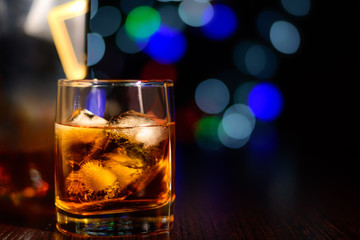 glass of whiskey with ice on bokeh background