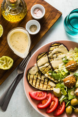 an appetizing dinner or lunch from a salad with tomatoes, grilled eggplants and legume falafel with sesame tahini dressing. Vegan healthy food for the whole family