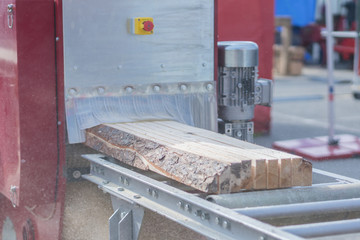 The log, sawn to the board, comes out of the sawmill. Woodworking industry.
