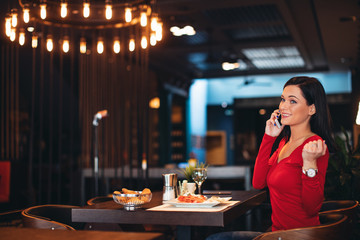 Young woman on breakfast talking on the phone in a restaurant