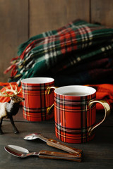 Holiday mugs with hot tea on wood table
